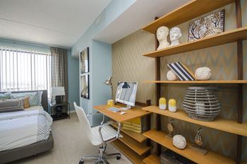 a bedroom with a desk with a computer and a bed